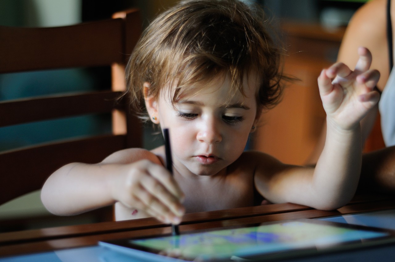 Little girl painting with a digital tablet at home. Little girl, two years old, painting with a digital tablet at home.